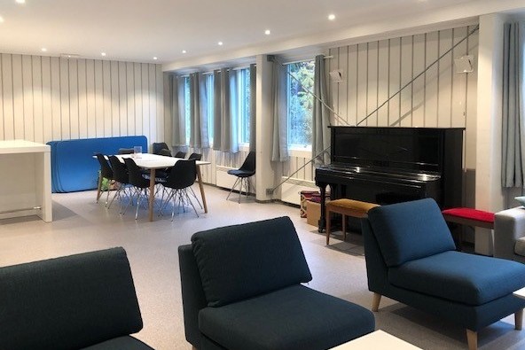 Peisestue med piano, spisebord og sittegrupper.