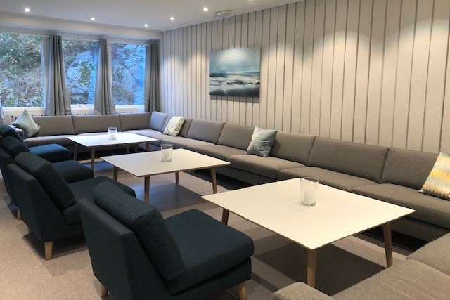 Peisestue med sittegrupper og bord i underetasjen på Barbu menighetshus.